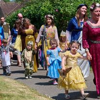 young children process into the arena accompanied by teachers and helpers on a sunny day