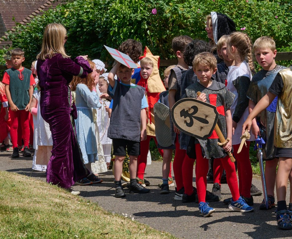 children from school in medieval costume. The boys in tabbards and red tights with swords and shields