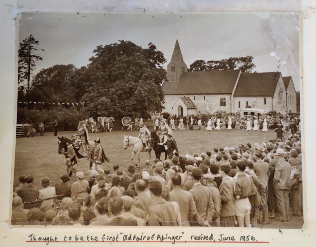 A sepia coloured photo of what is thought to be the first fair in 1956. St James in the background and the procession is lead with 3 horses being ridden