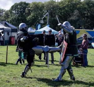 2 knights in medieval armour with one kicking the others shield
