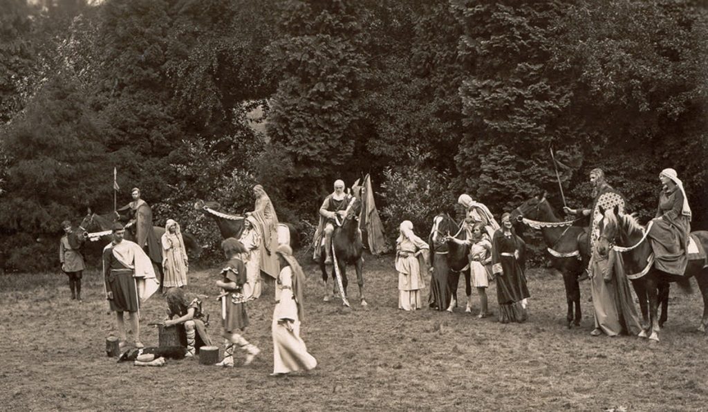 black and white photo with villagers in smart costumes many on horses
